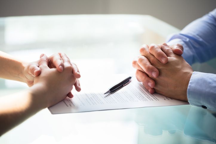 Close-up Of Two Businesspeople Hand With Document On Desk